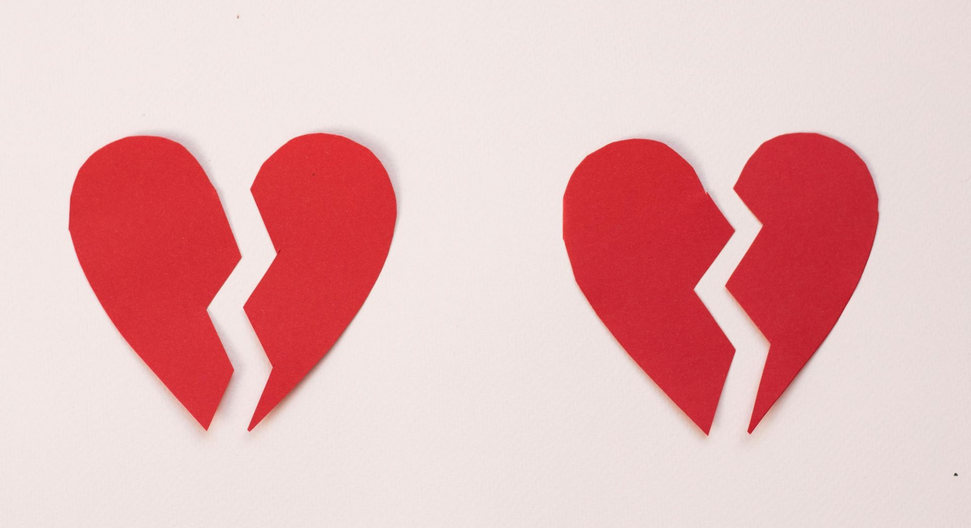 Two broken red heart symbols on a light background.