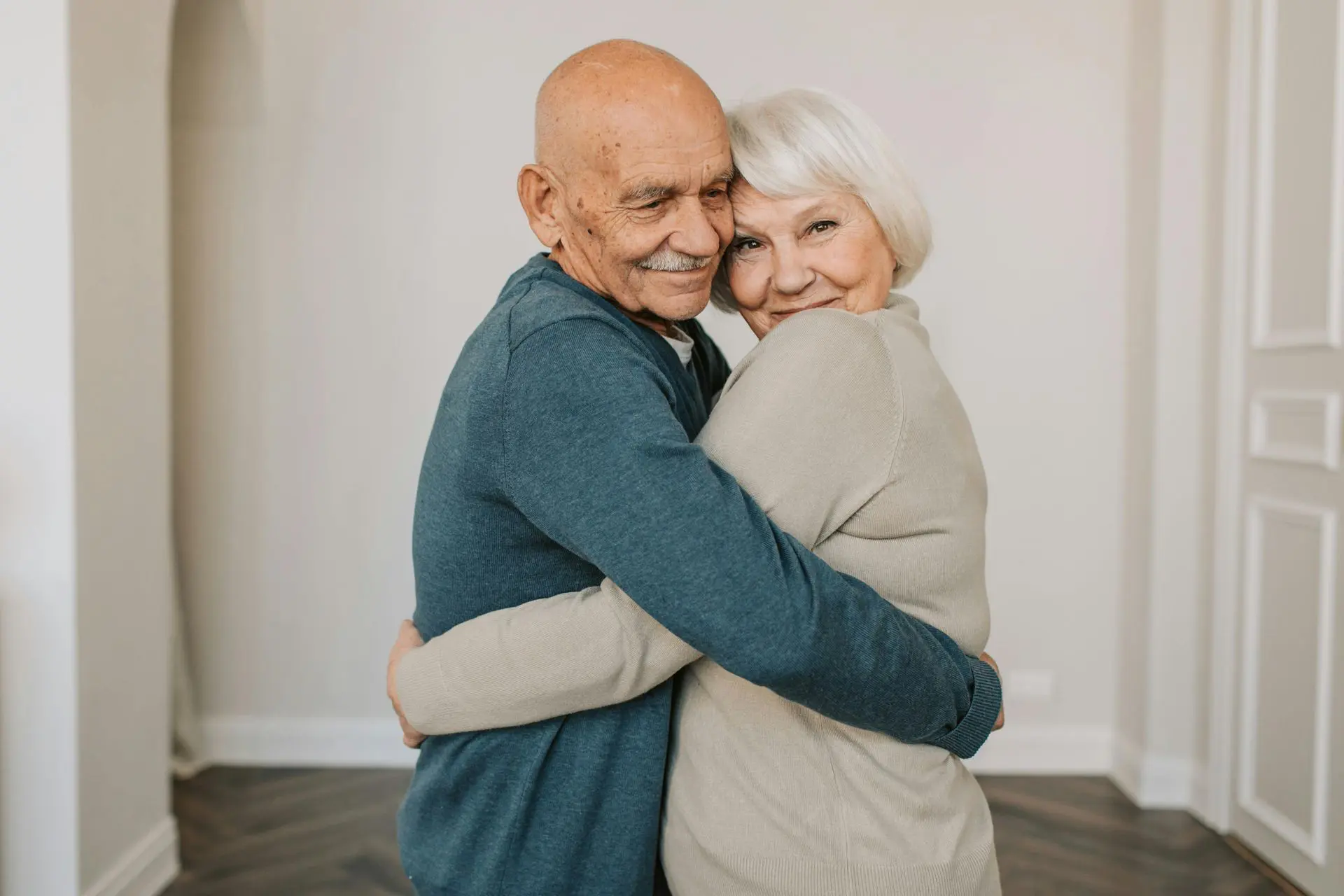Elderly couple sharing a warm hug indoors.